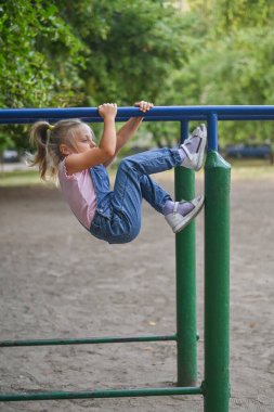 Spor sahasında kot takım elbiseli dört yaşında bir kız.