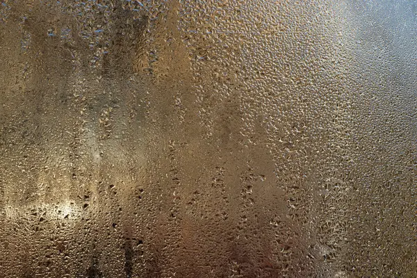 Yoğunlaşma, buzlu cam yüzeyinde narin su boncukları oluşturur. Islak bardağa damlatıyor. Pencere camındaki su damlacıklarının soyut dokulu arka planı. ıslak cam arkaplan