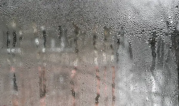 Damlacıklı nemli pencere camı doğal bir model oluşturuyor. Soyut arka planlar, tasarım projeleri veya yumuşak, duygusal bir ruh hali iletmek için ideal.