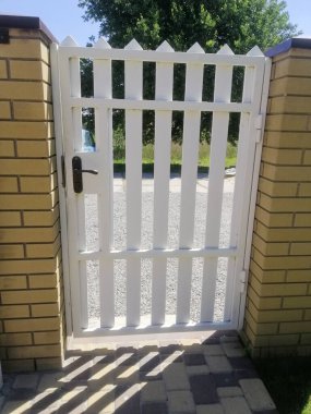 Modern beyaz kapı kırsal alana girişi işaret ediyor. Modern beyaz güvenli çit kapısı, güzel çitler. Banliyö mülküne özel ama misafirperver bir yaklaşım. Geometrik kesinlik uzayı tanımlar