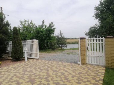 Açık beyaz kapı, ağaçlı ve çakıllı özel avluya açılıyor. Ağaçlar ve kapı rahat kırsal bir ortam yaratır. Geçit görsel odaklanma için vurgulandı. mahremiyet ve güvenlik kavramını aç 