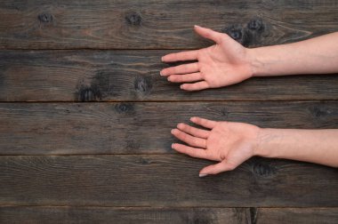 Avuç içlerinin doğal ahşap üzerine nazikçe konması. Eller konuşmadan konuşur. Minimalist kadın eli ve yıpranmış masa. Avuç içi açık kadın el hareketi. Güven ve açıklık kavramı