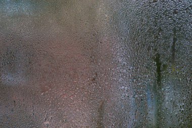 Küçük su damlacıkları, battaniyeli sis camları. Bazı damlacıklar aşağı doğru kaymaya başladı bile. Apartman penceresinin ıslak camı yüksek nem nedeniyle doğal desenli soyut bir arkaplan oluşturdu.