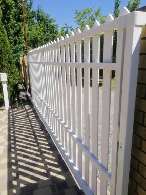 Dikey fotoğraf Güzel beyaz çit zarifçe özel bahçeyi sarar, Temiz çizgileri estetik çekicilikle mahremiyeti ifade eder. Eskrim konut alanı için mükemmel bir sınır oluşturur.. 