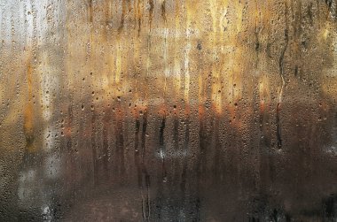 Su damlacıkları ve bulanık manzaralı ıslak cam pencere. Yoğunlaşma doğal soyut kalıplar yaratır. Küçük su damlalarıyla kaplı sisli pencerelere yakın çekim. Bulanık nemli cam yüzey arkaplanı.