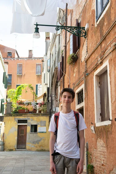 ハンサムな幸せな笑顔ティーン男の子ポージング上洗濯あります乾燥ハング上の服で古代ヴェネツィアの街 — ストック写真