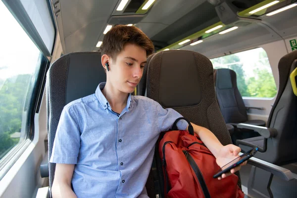 stock image Handsome cheerful teen boy riding a train and using a smartphone