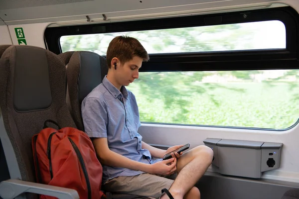 stock image Handsome cheerful teen boy riding a train and using a smartphone