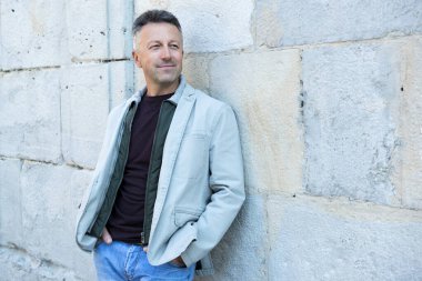 Orta yaşlı bir adam antik şehir mezarlığına poz veriyor. Yakışıklı, olgun bir adam. Açık hava erkek portresi. 