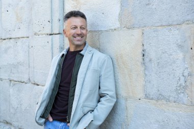 Orta yaşlı bir adam antik şehir mezarlığına poz veriyor. Yakışıklı, olgun bir adam. Açık hava erkek portresi. 