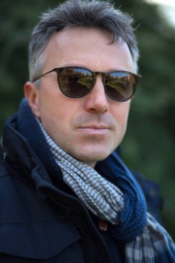 Yakışıklı, olgun bir adam. Açık hava erkek portresi. Güneş gözlüklü çekici, kendinden emin, orta yaşlı bir adam..