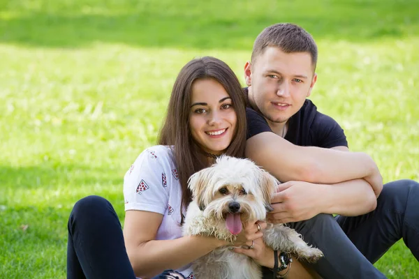年轻的夫妇与小狗 美丽的微笑的年轻女子和男子的肖像抱着可爱的小狗 夏季公园户外 — 图库照片