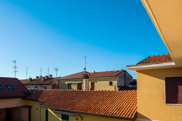 Tiled roofs of houses with antennas in a small town in Italy against the background of the blue sky