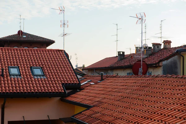Tiled roofs of houses with antennas in a small town in Italy against the background of the evening sky