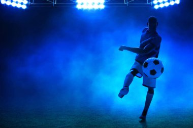 Geceleri boş stadyumda topa vuran genç profesyonel futbolcunun üç boyutlu gölgesi.
