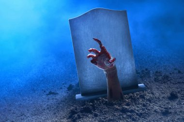 Mezar taşından yükselen zombi eli sis ve Cadılar Bayramı temalı
