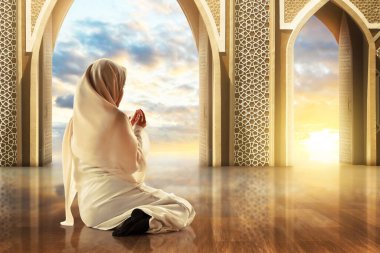 Genç Asyalı müslüman kızın cami kapısında dua edişinin arkası. Kemerli İslami süs, güzel günbatımı gökyüzü, Kurban Bayramı Mübarek konsepti.