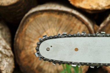 Odunların arka planında testere bıçağı ve zincir var.