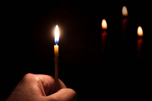 在黑暗的背景上拿着燃烧的蜡烛的手 — 图库照片