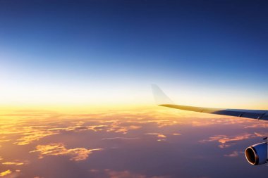 Gün batımında bulutların üstünde, gökyüzünde bir uçak.