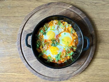 Tahta masadaki siyah tavada sebzeli Tayland usulü sahanda yumurta.