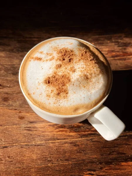 Güneşli bir sabahta, ahşap bir masada tarçınlı kahve.