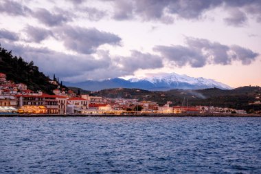 Yunanistan 'ın Laconia şehrinde kışın Gytheio' nun üzerinde gün batımı. Taigetos Dağları 'nın karlı zirveleri uzaklardan görülüyor..