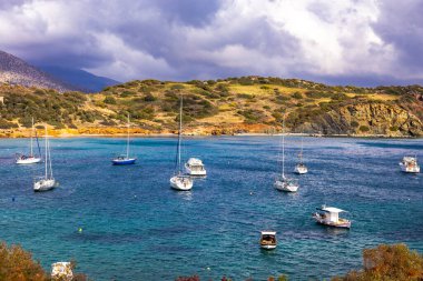 Scenic view of sea bay with boats and beach in background, in winter, in Anavyssos, Greece. Image taken from Agios Nikolaos Peninsula. clipart