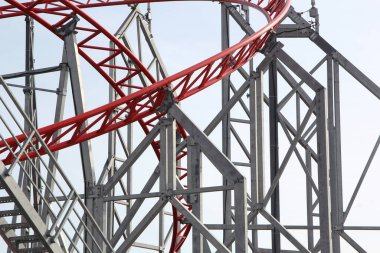Metal roller coaster close up with red rails in an amusement park