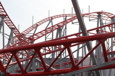 Metal roller coaster close up with red rails in an amusement park