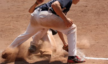 Amatör beysbol oyuncuları kalenin yakınındaki toprak sahada.