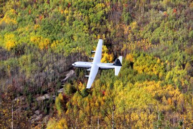 Water bomber making test run over treetops in remote area clipart