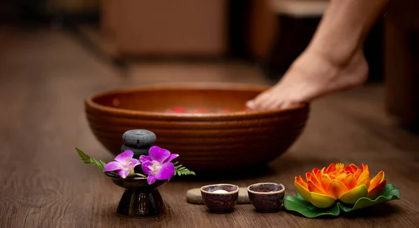 Woman soaks her feet in a bowl with rose flower petals. Foot Spa Concept
