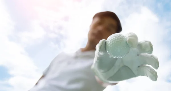 Golfer putting golf ball on tee on golf course. Hand putting golf ball