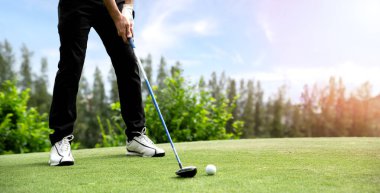Golf sahasında golf oynayan erkek golfçü. Golfçü golf sahasında golf topuna vurmak için şoför kullanır..