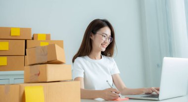 Asyalı çevrimiçi satıcılar satış sitelerinden sipariş alıyorlar. Sonra ürünleri müşterilere teslim etmek için paketleyin..