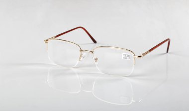 Tıp ve optik - Modern altın okuma gözlüğü beyaz arkaplan ve yansıma