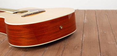 Musical instrument - back view classic acoustic guitar on a white wall background and wooden floor. clipart