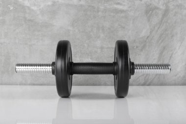 Spor ve zindelik - Ön manzara iki ağırlığı beton arka plan olan siyah dambıl