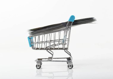 Beyaz arka planda bir alışveriş arabasında 100 dolarlık banknotlar yığıldı.