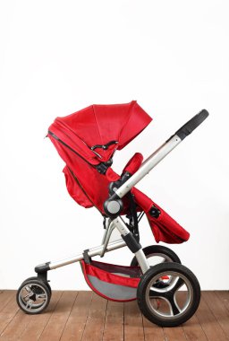 Beyaz bir duvar ve ahşap zemin üzerinde kırmızı evrensel bebek arabası