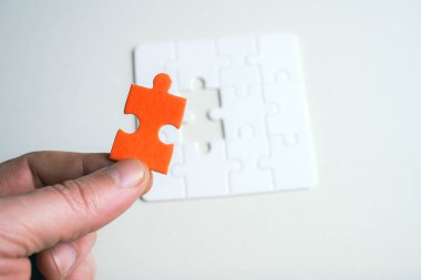 Bir kişi elinde kırmızı bir yapboz parçası tutuyor. Bulmacanın anahtar bir parçası eksik. İş konsepti. Beyaz arkaplan.