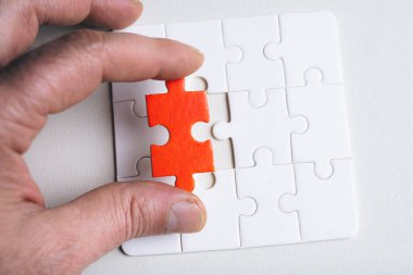 Bir kişi üzerinde kırmızı nokta olan bir yapboz parçası tutuyor. Yapboz parçası kayıp ve o kişi onu bulmaya çalışıyor. Bulmacayı tamamlamak için çalışan kişi olarak kararlılık kavramı ve odaklanma