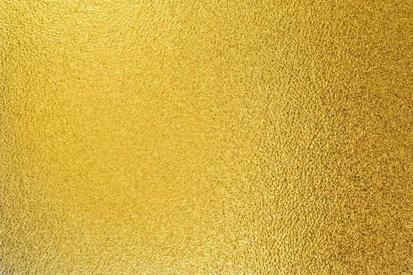 Gold wall texture background. Yellow shiny gold foil paint on wall sheet with gloss light reflection, vibrant golden luxury wallpaper