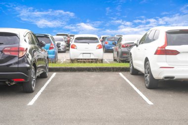 Asfalt otoparka park edilmiş bir araba ve beyaz bulutlu ve mavi gökyüzü arka planlı boş bir park alanı. Temiz ozon ve yeşil çevre kavramlı açık hava ulaşım parkı.
