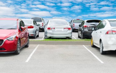 Depoda arka arkaya arabaları park ediyor. Araç nakliyesi envanter malları. Beyaz bulutlu ve mavi gökyüzü arka planlı büyük bir asfalt otoparka park edilmiş bir araba. Açık hava parkı lo
