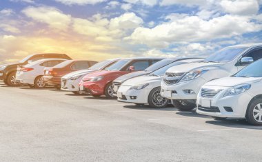 Depoda arka arkaya arabaları park ediyor. Araç nakliyesi envanter malları. Beyaz bulutlu ve mavi gökyüzü arka planlı büyük bir asfalt otoparka park edilmiş bir araba. Açık hava parkı lo