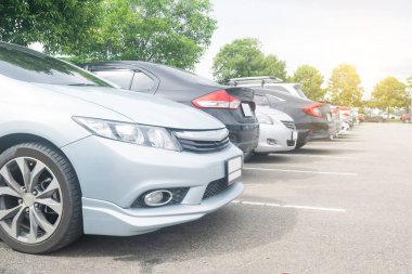 Depoda arka arkaya arabaları park ediyor. Araç nakliyesi envanter malları. Büyük asfalt park alanına park edilmiş, ağaçların arkasına park edilmiş. Açık hava parkı lo