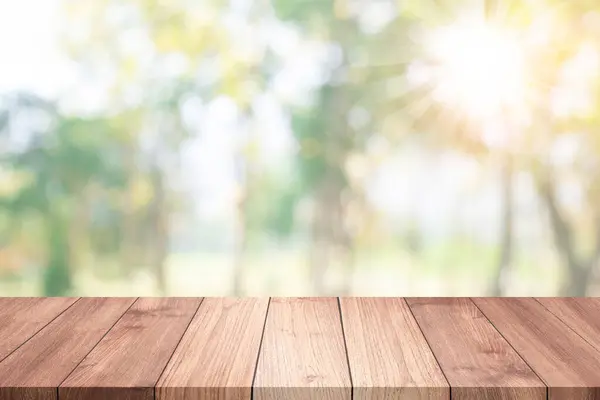 Empty wooden table top or counter sun and sunlight light blur bokeh of green leaves and trees nature in green park spring garden. Template mockup display montages product. Wood table plank background