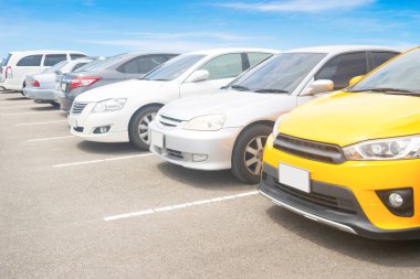 Depoda arka arkaya arabaları park ediyor. Araç nakliyesi envanter malları. Beyaz bulutlu ve mavi gökyüzü arka planlı büyük bir asfalt otoparka park edilmiş bir araba. Açık hava parkı lo